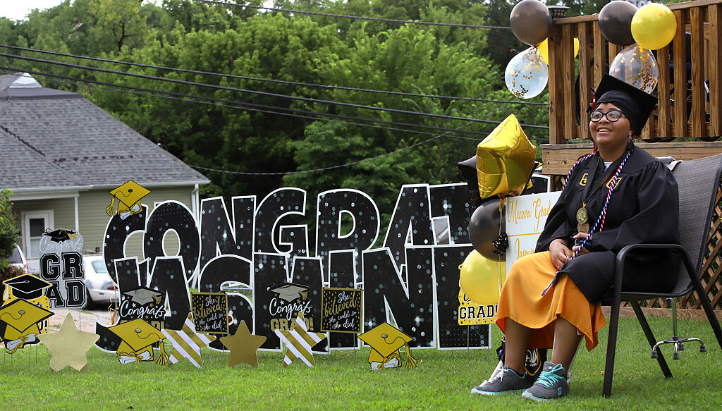 Jasmine-Kay Johnson greets friends and family from her yard during a graduation parade on Saturday